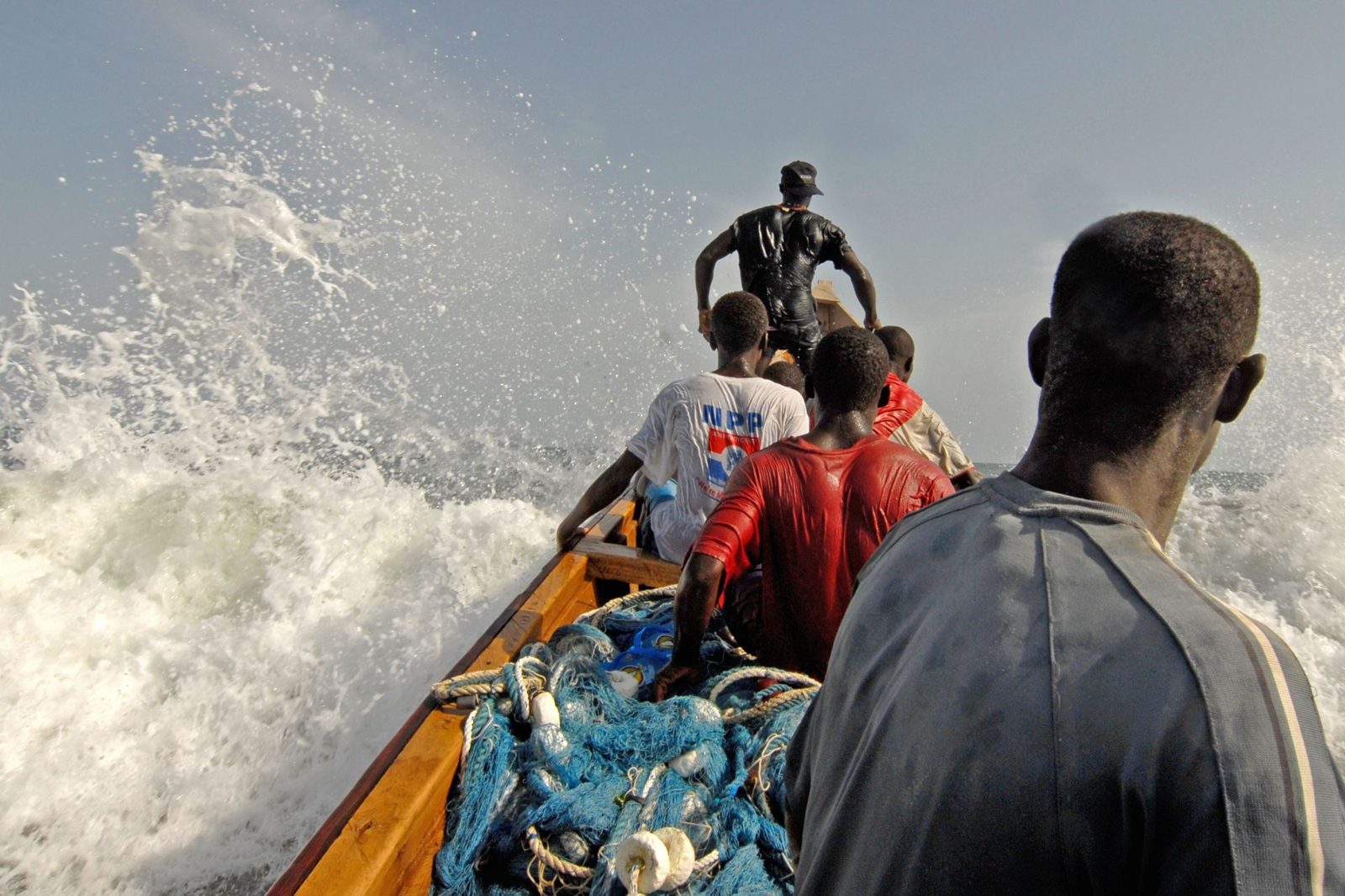Fishermen in a canoe riding the waves, Ghana