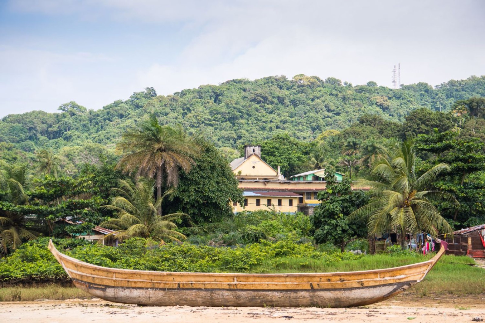 Wooden canoe on the shore with green hills behind, Liberia